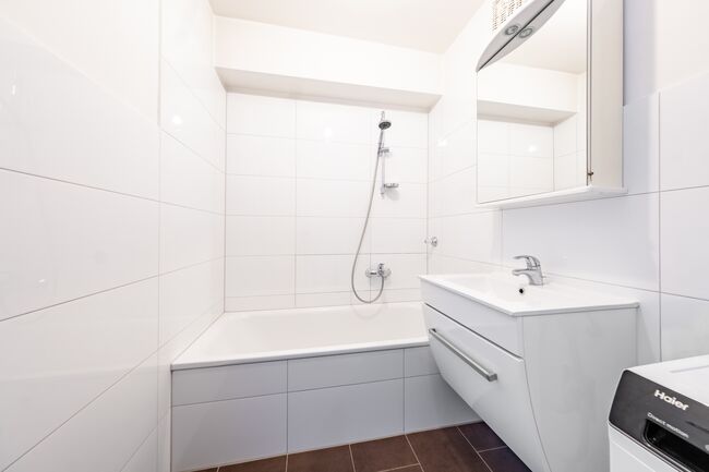 Modernes Bad mit Wanne, hellen Fliesen und gepflegter Ausstattung.